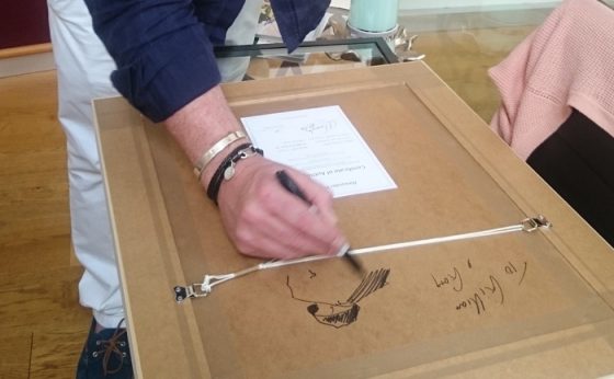 Alexander Millar signing an artwork for a customer